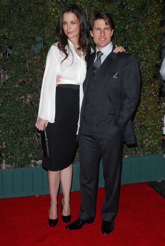 Katie Holmes in a black skirt and shirt with Tom Cruise