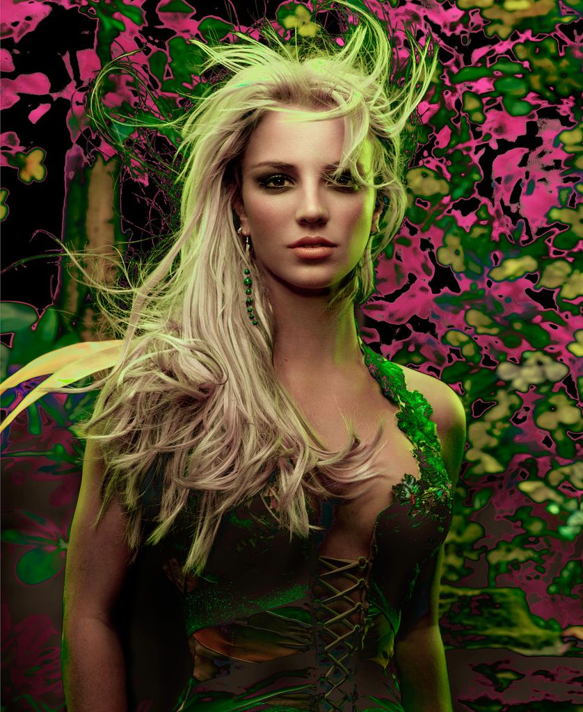 Britney Spears poses in front of a floral wall in a green dress for the Onyx Tour promotional pictures shot by Markus Klinko
