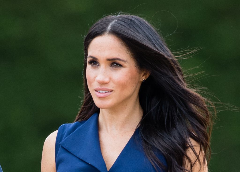 meghan markle with hair flowing in the wind and navy dress