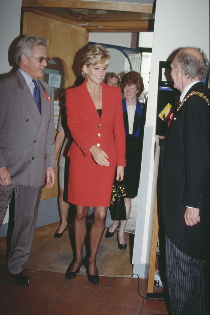Princess Diana in a red suit meeting people at London Lighthouse