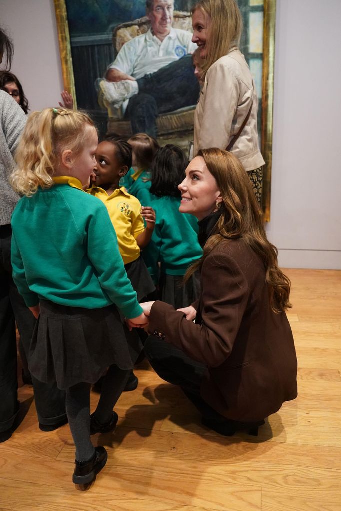 woman talking to bunch of children in gallery 