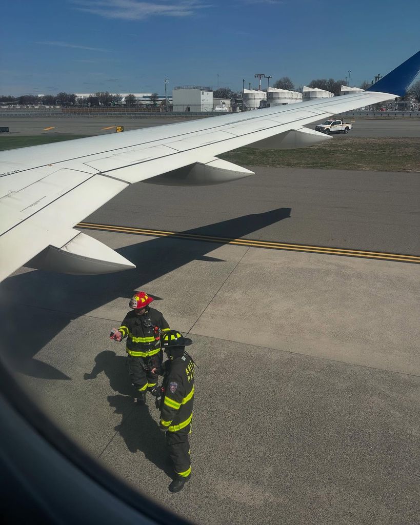 firefighters beside wing of plane
