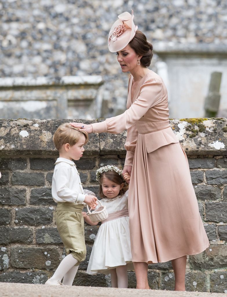 Kate Middleton with her hand on Prince George's head while holding Princess Charlotte's hand