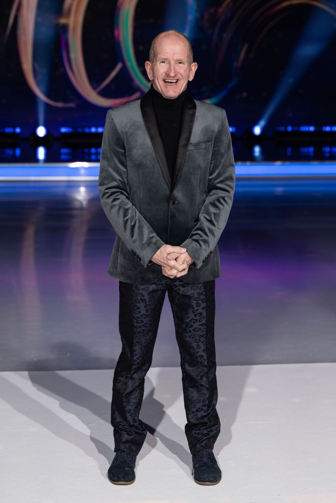 Eddie 'The Eagle' Edwards in a grey velvet suit in front of the ice rink