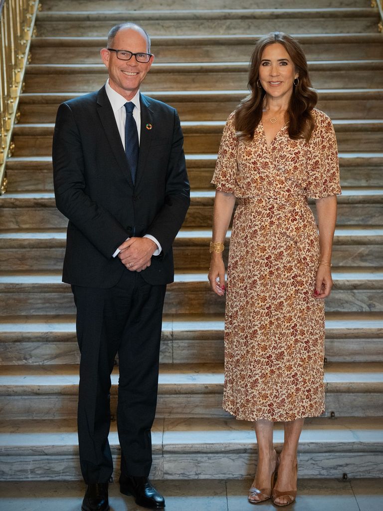 Queen Mary in brown and white dress posed with man in suit