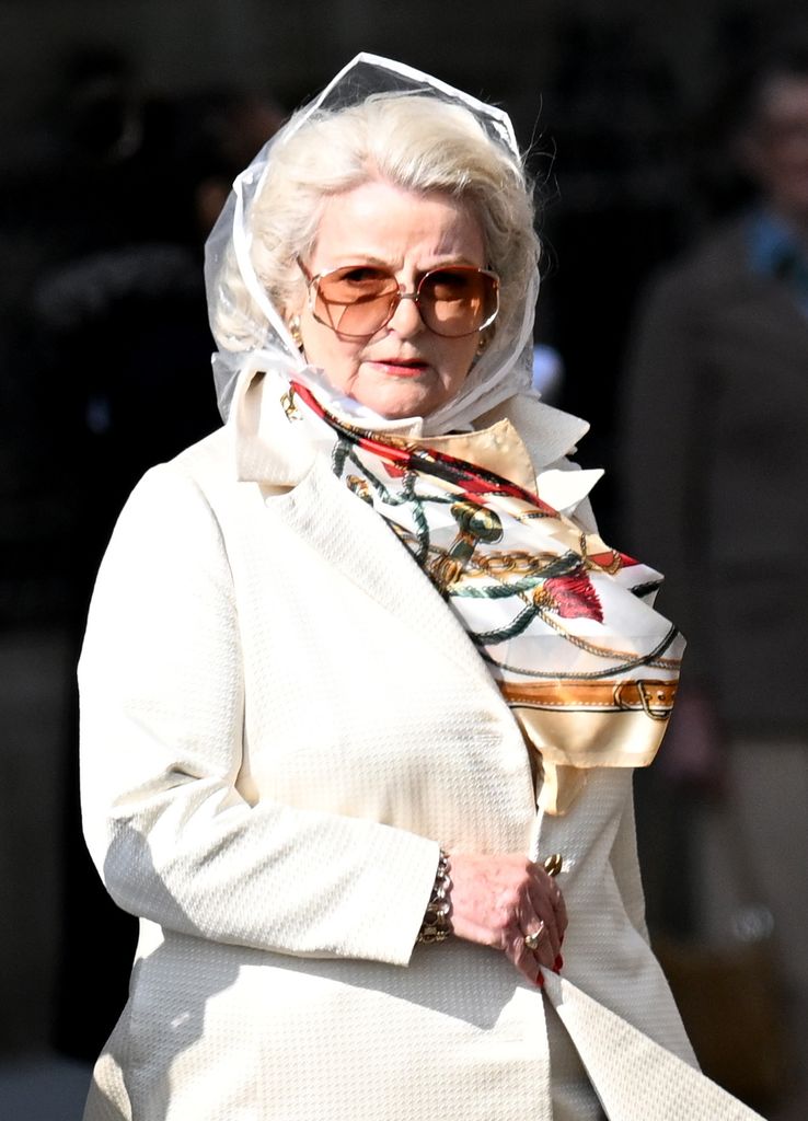 woman in cream trench coat and glasses