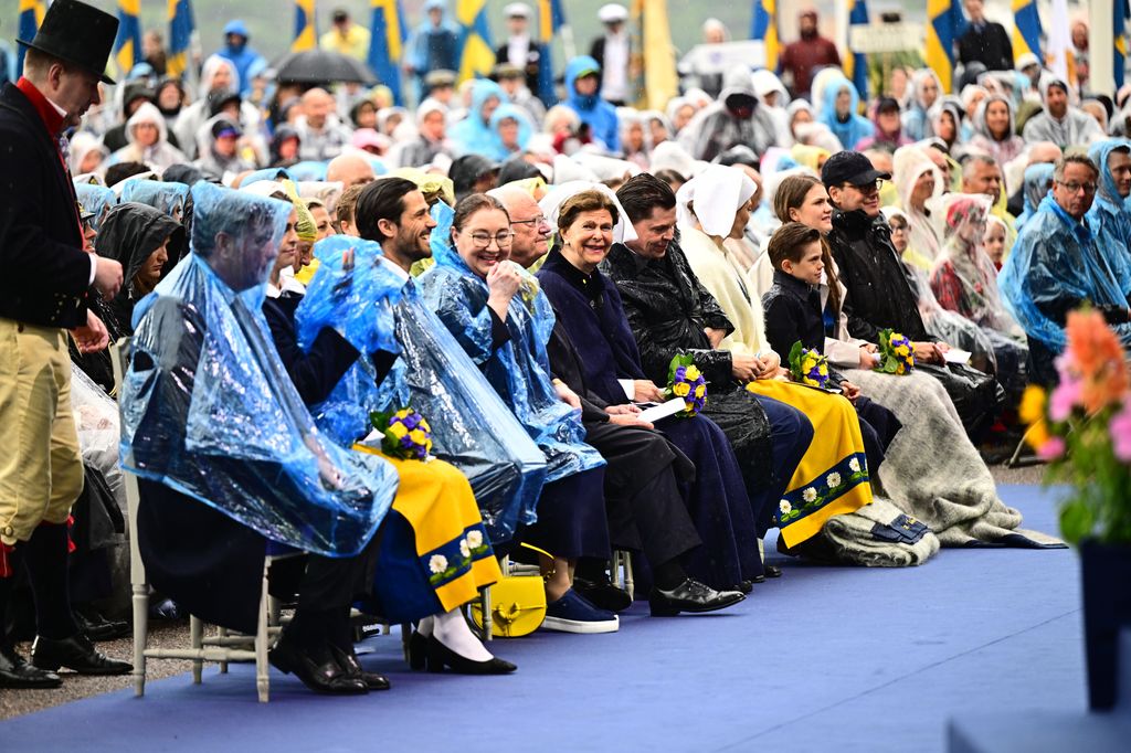 Members of the Swedish royal family and public sitting in ponchos