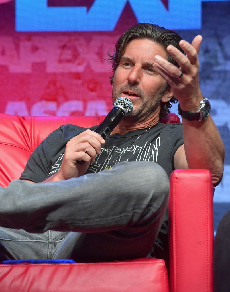 photo of brett james sitting on a red couch holding a mic