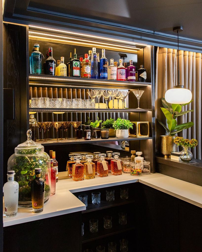Home bar stocked with martini glasses and alchohol at Zara McDermott and Sam Thompson's home