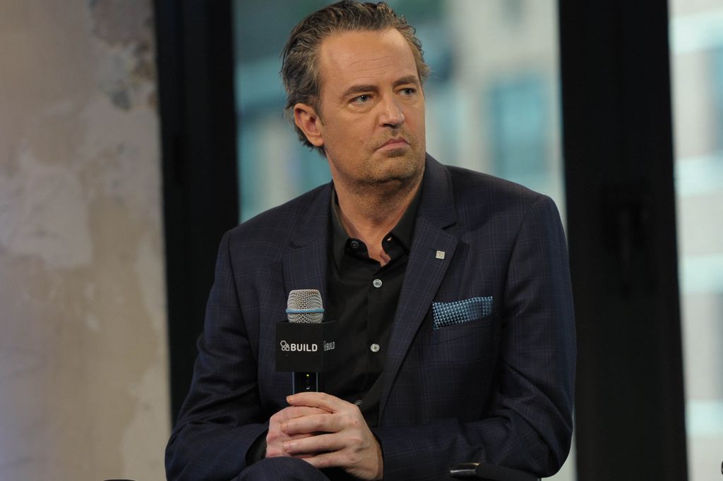 Matthew Perry in a black shirt and blue jacket