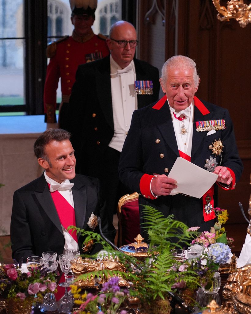 France's President Emmanuel Macron (L) smiles as Britain's King Charles III delivers a speech during a State Banquet 