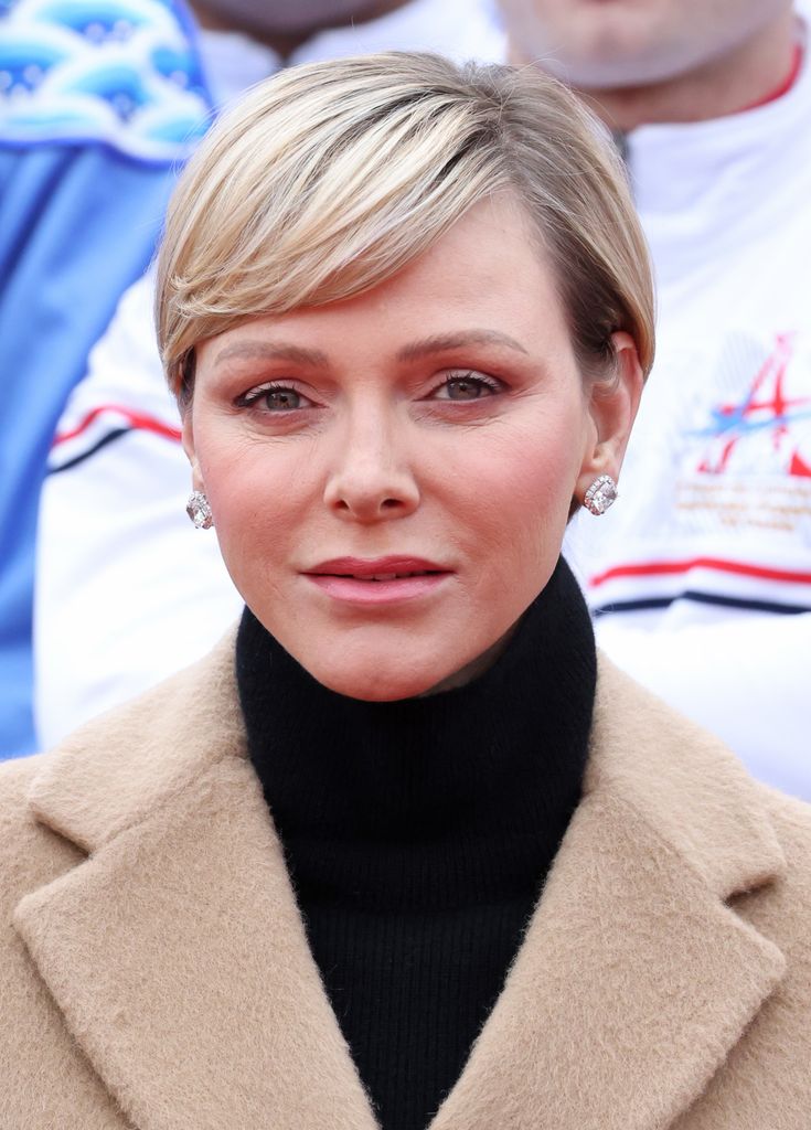 Princess Charlene wears a black turtle-neckh top and cream coat