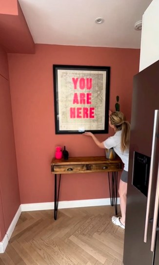 Sian Welby putting up a stylish print in her home