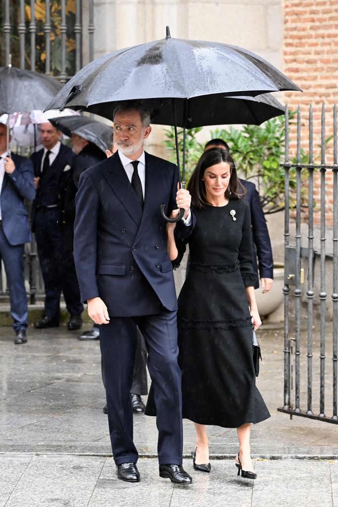King Felipe holding umbrella walking with letizia