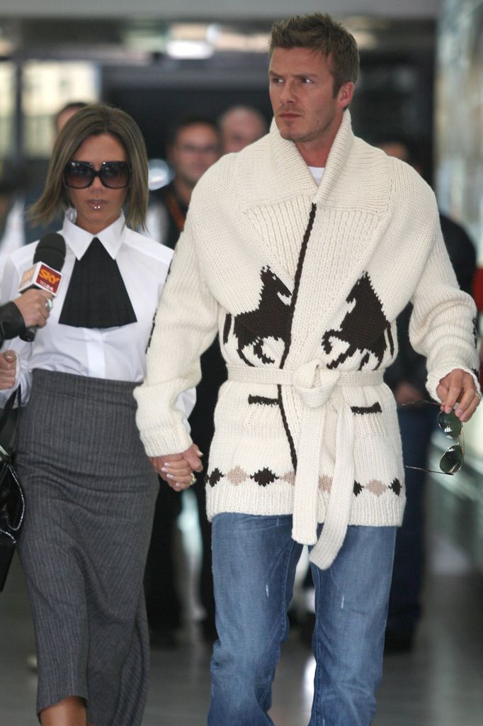 David Beckham wears a long length thick knit cardigan with horse embroidery, tied at the waist and paired with jeans. 