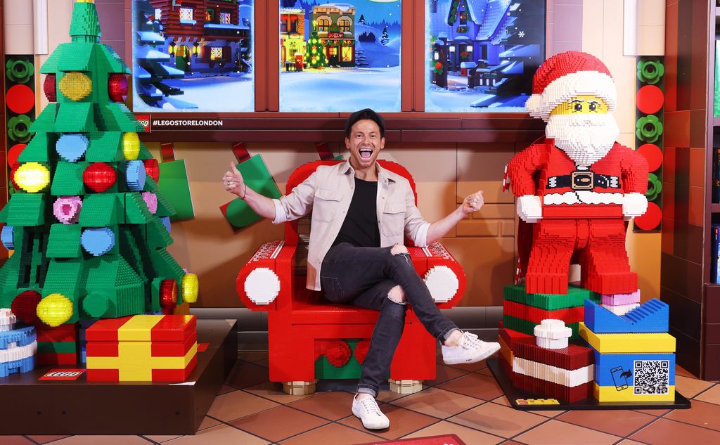 Joe Swash sat on a LEGO seat with a Santa figurine and Christmas tree nearby