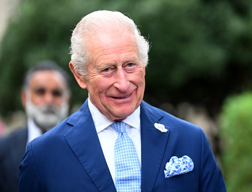 King Charles smiling in a blue suit