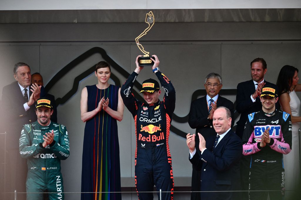 Winner Red Bull Racing's Dutch driver Max Verstappen holds up his trophy, accompanied by the Monaco royals
