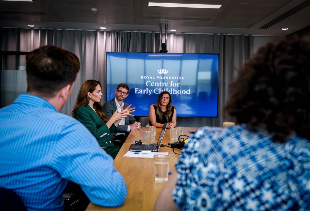 Kate Middleton talking at table in front of Royal Foundation logo