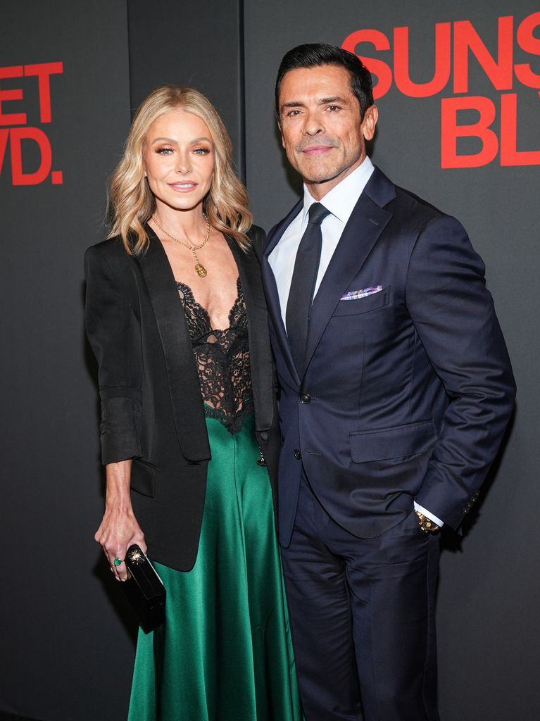 Kelly Ripa in black blazer and lace dress and Mark Consuelos in navy suit 