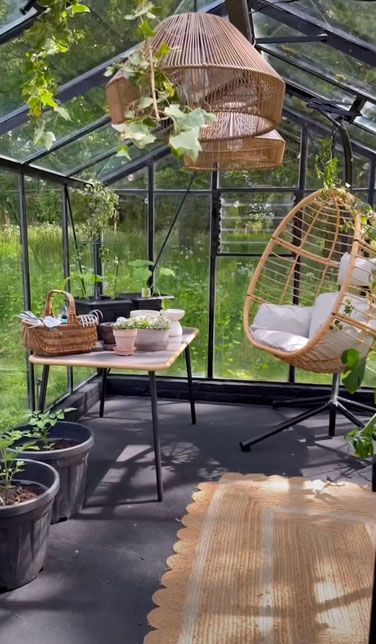 Stacey Solomon inside of greenhouse with hanging lamps and egg chair
