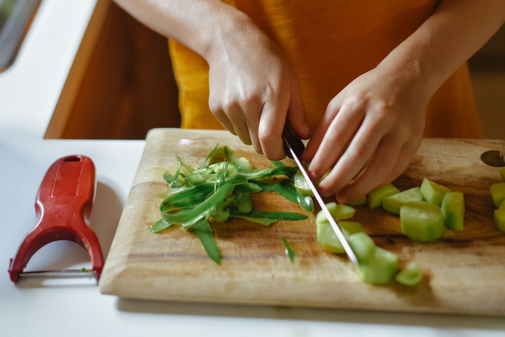 Close up on Hands While Cutting a Cucumber with a Knife