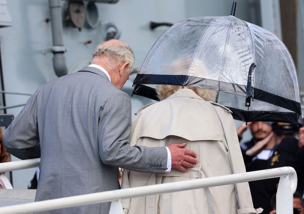 Charles places hand on Camilla's back as they board HMS Iron Duke