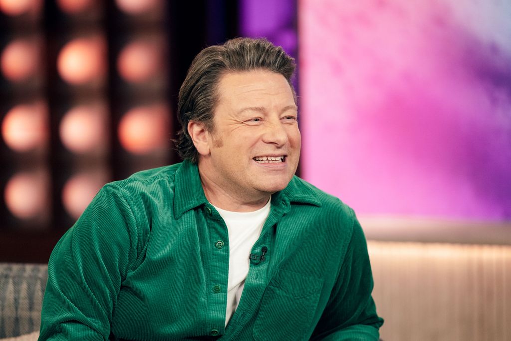 Jamie Oliver smiling in a green outfit