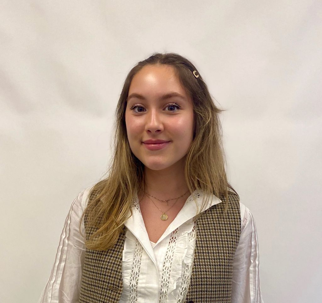 headshot of a young woman in a white shite and a tweed waistcoat