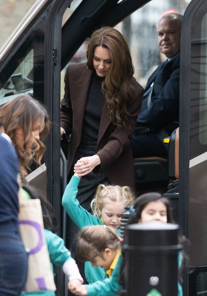 Kate Middleton holding little girl's hand as she steps off bus