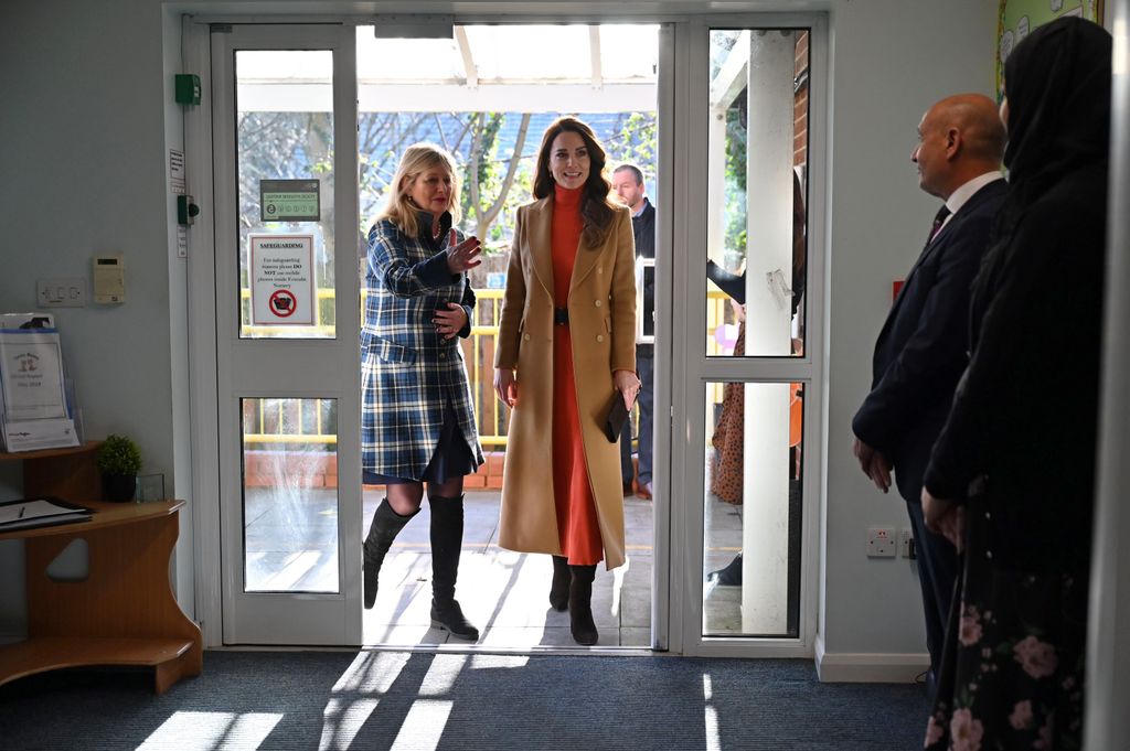 The Princess of Wales entering through door in orange outfit
