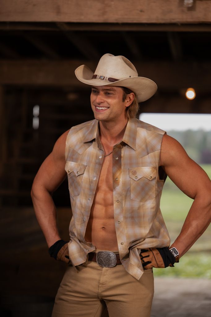 man standing in barn in waistcoat and cowboy hat
