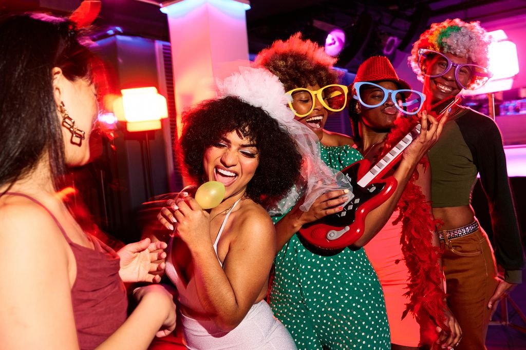 group of young people in costume at a bachelorette party singing and having fun in the discotheque