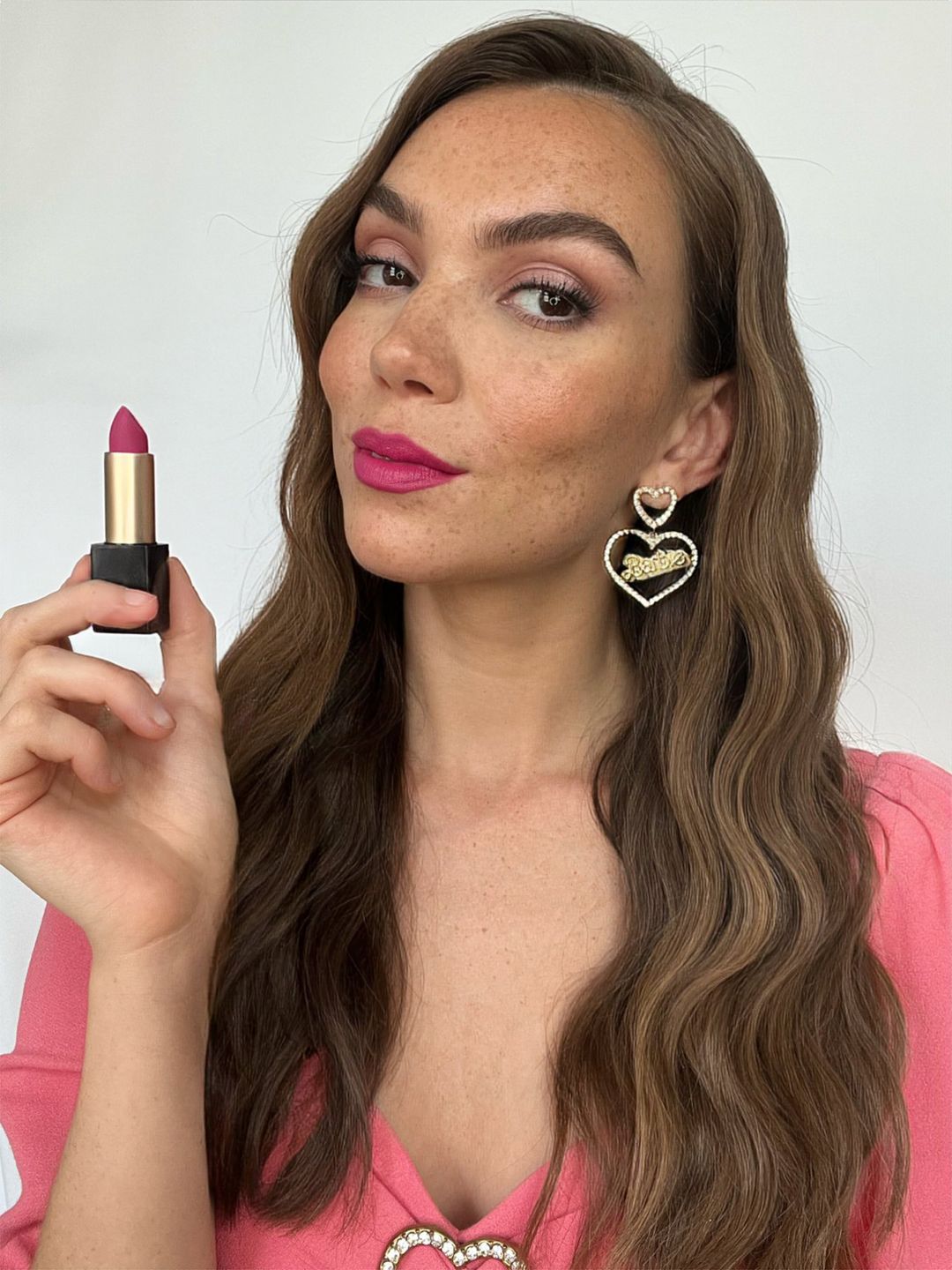 Makeup artist yasmin salmon holds a pink lipstick for a barbie inspired beauty look