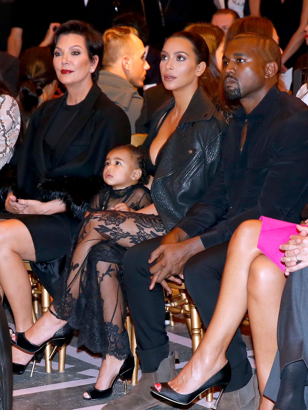 A toddler North West sat with her mom, dad and grandmother in a front row at Paris Fashion Week 2014