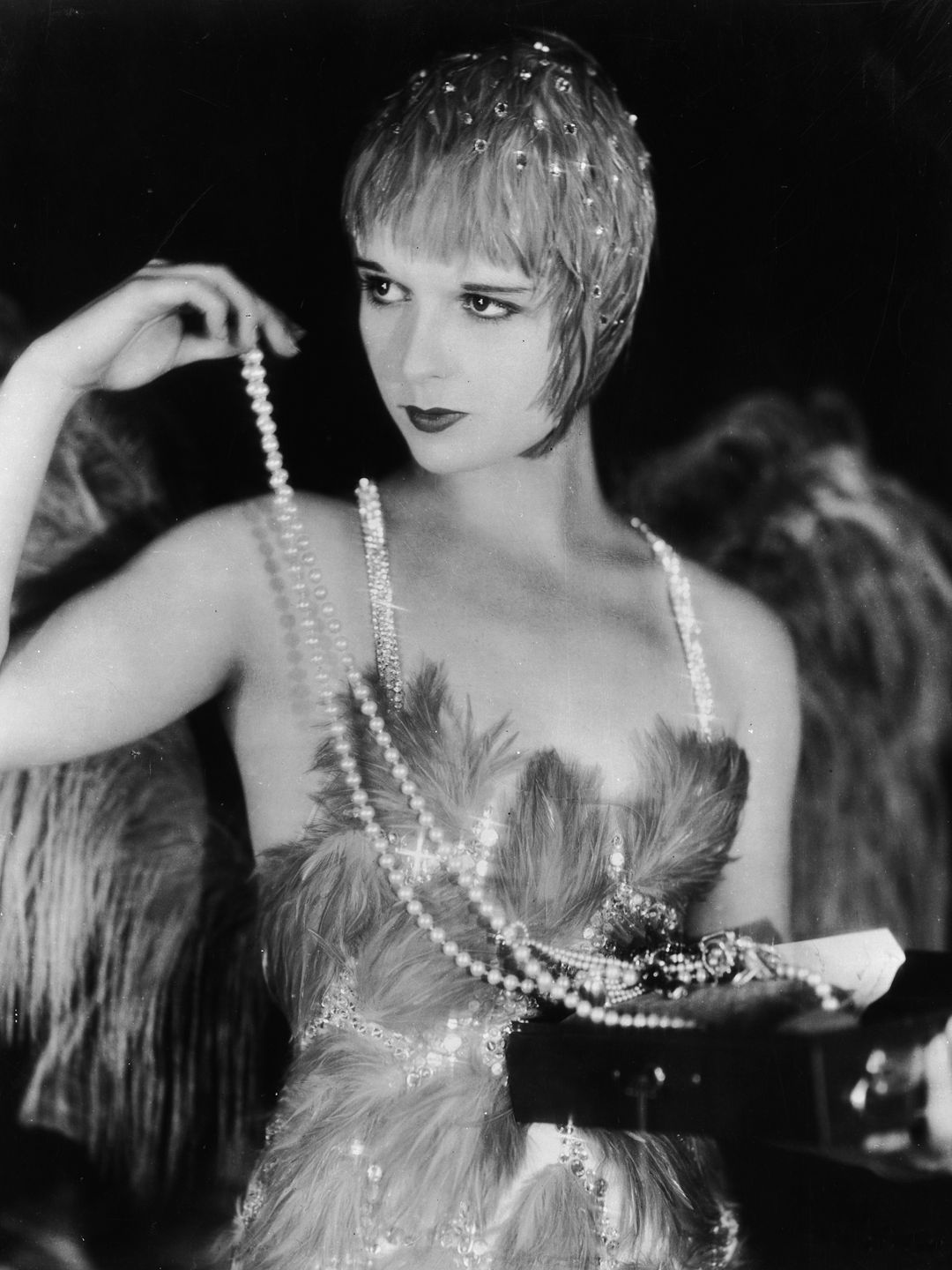 Louise Brooks holds a long string of pearls 
