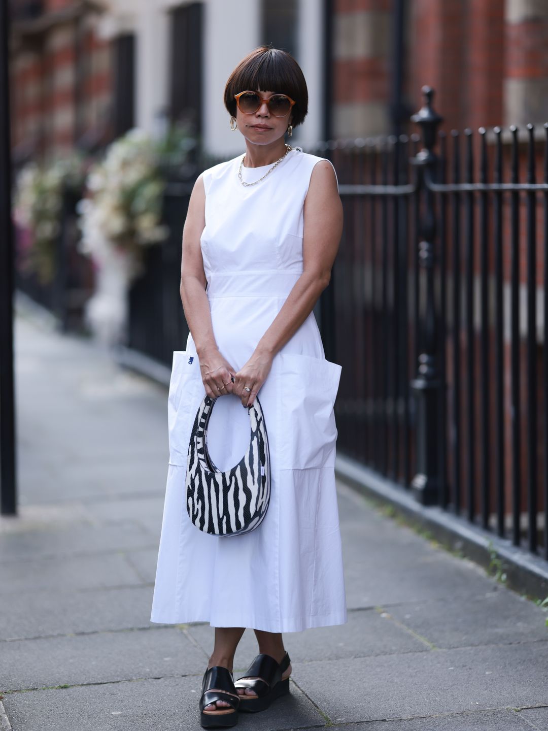 Woman wears a plain white dress with a zebra print bag