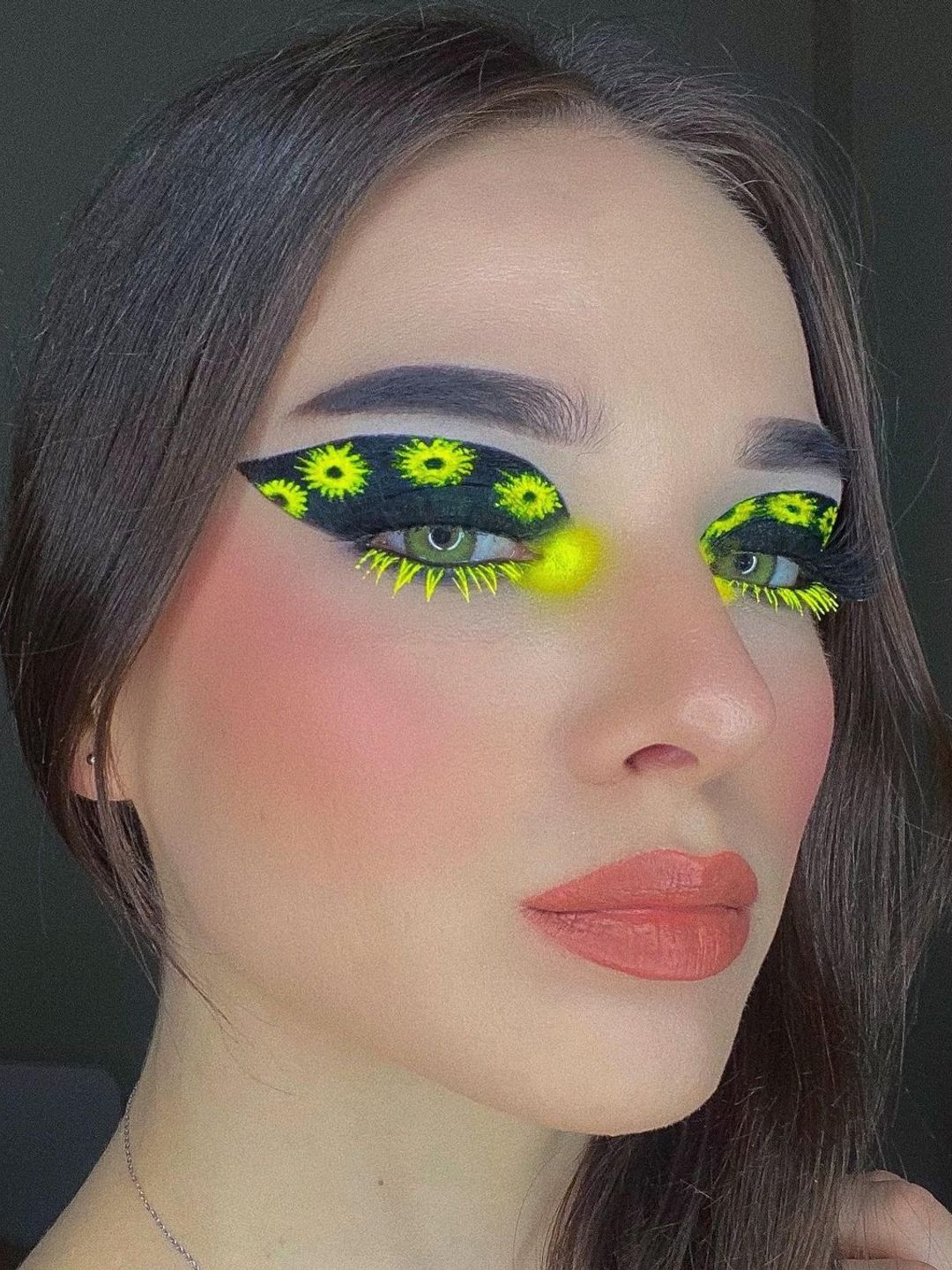Woman with thick black eyeliner and neon flower accents 