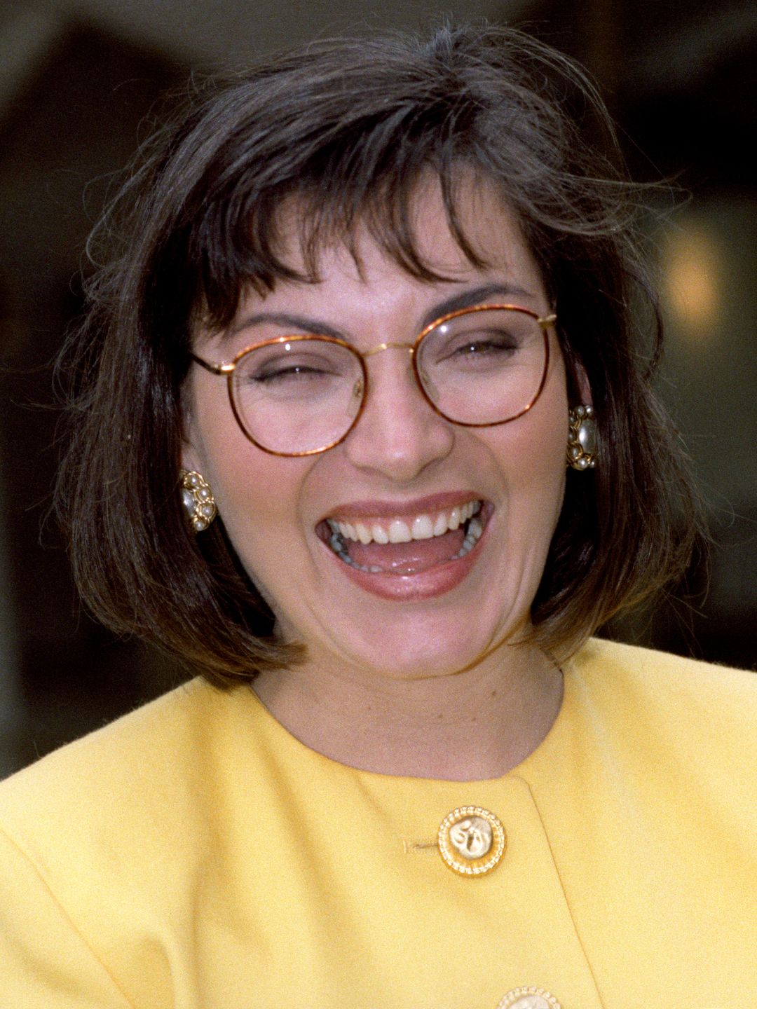 Lorraine Kelly laughing in a yellow top with short dark hair