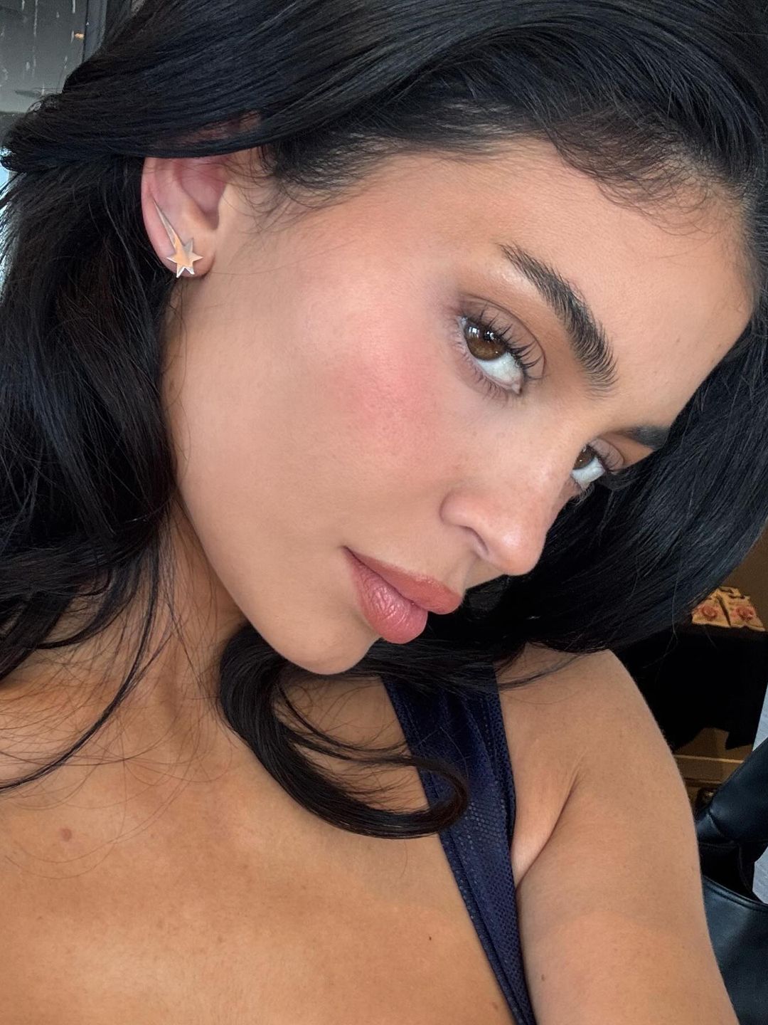 Kylie Jenner poses wearing a a set of custom silver earrings designed to look like the Sprinter logo