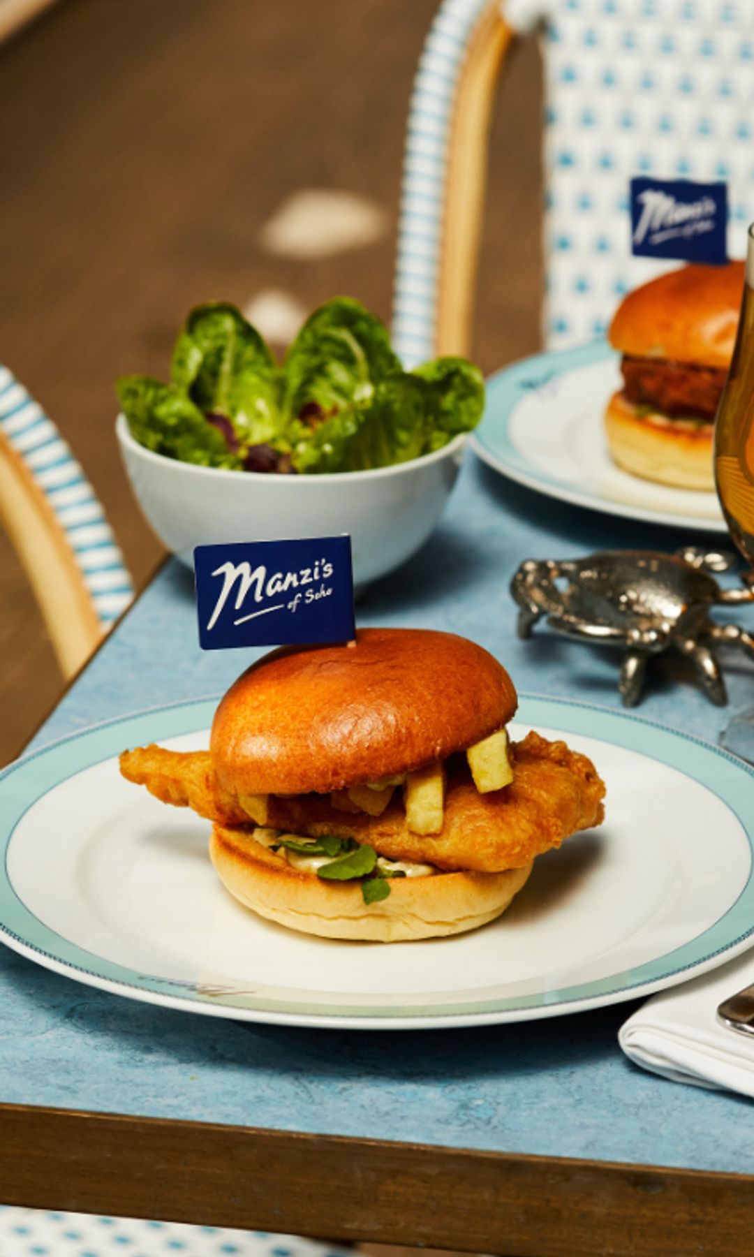A fush and chips burger next to a pint of beer