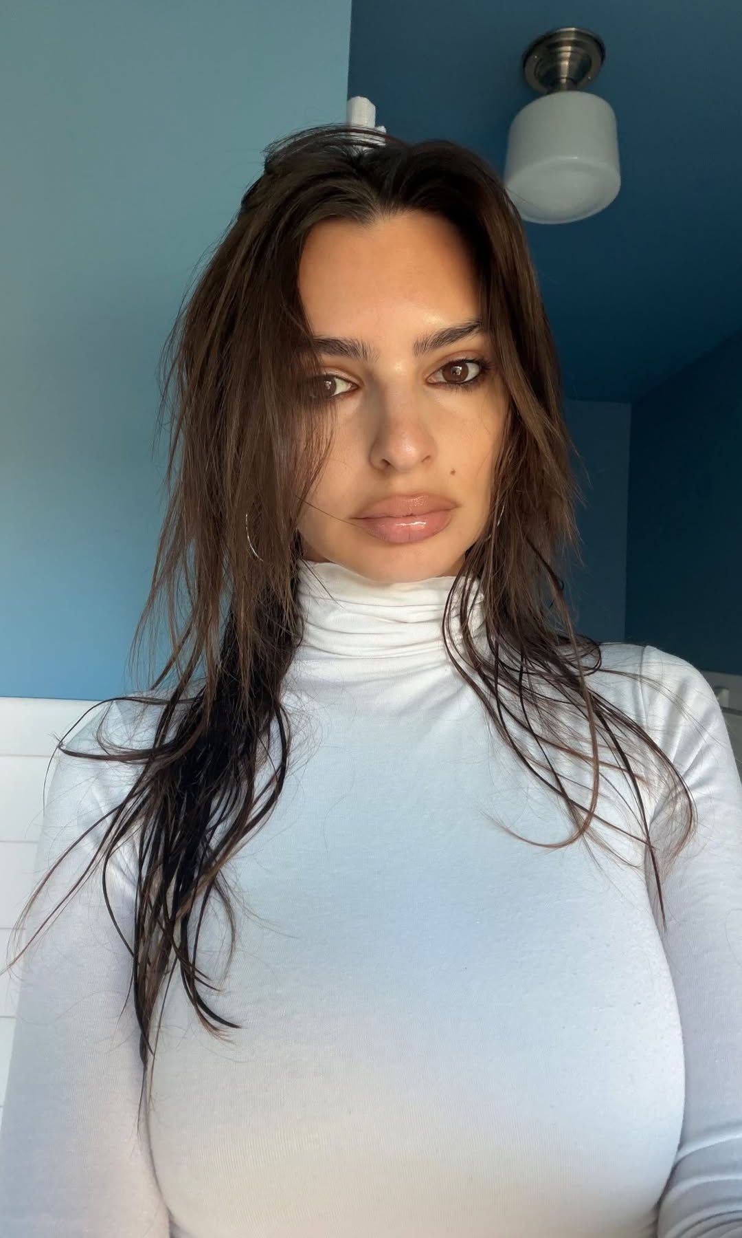 Emily Ratajkowski poses for a selfie in a white turtleneck 