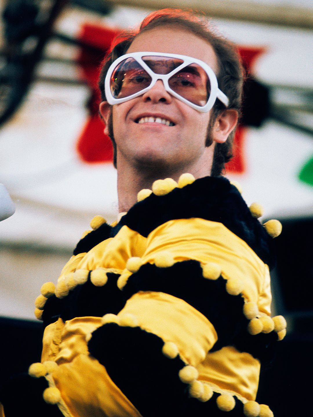 elton john in striped top playing piano