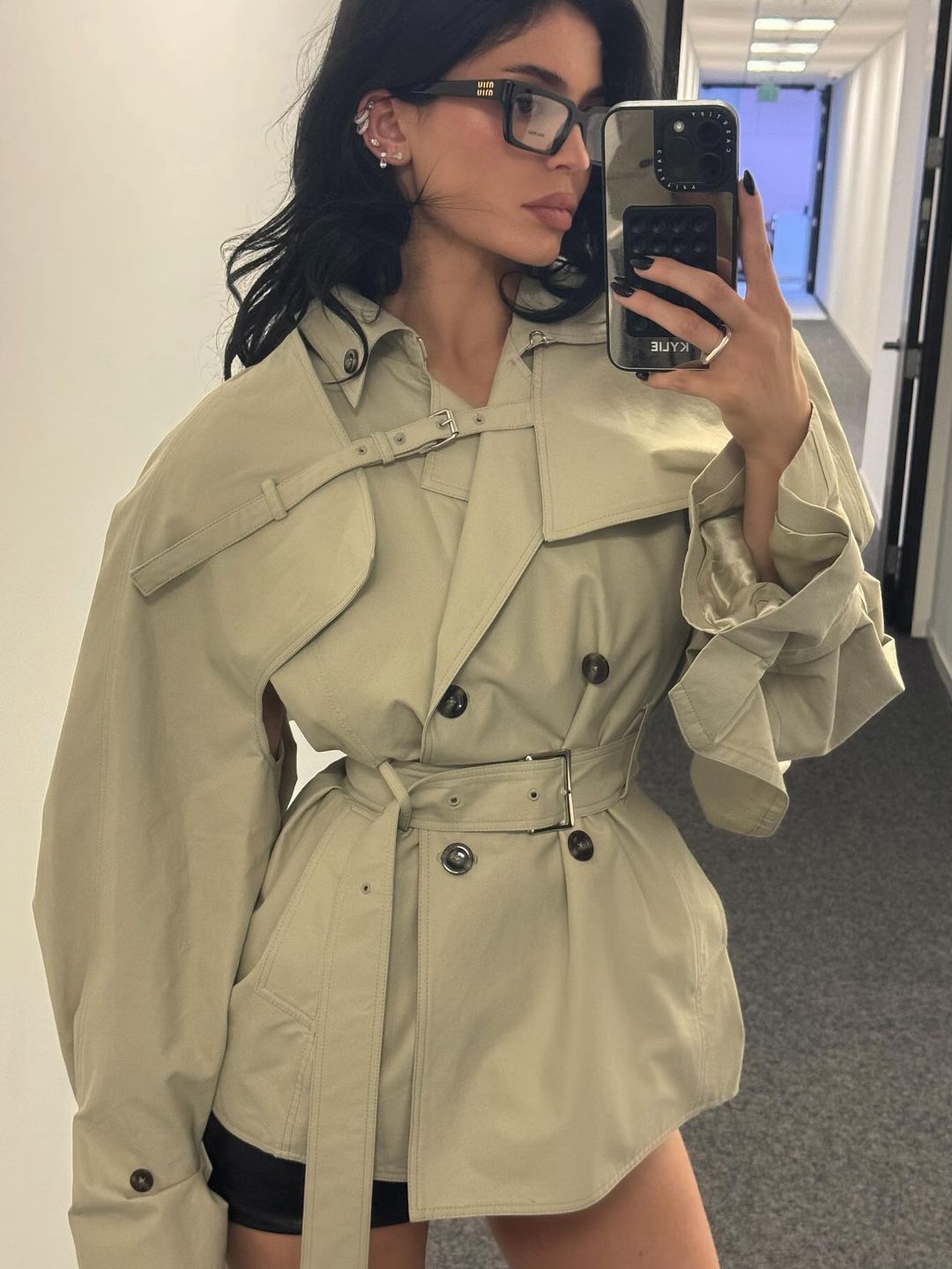 Kylie Jenner poses for a mirror selfie in a cropped trench and black leather mini skirt