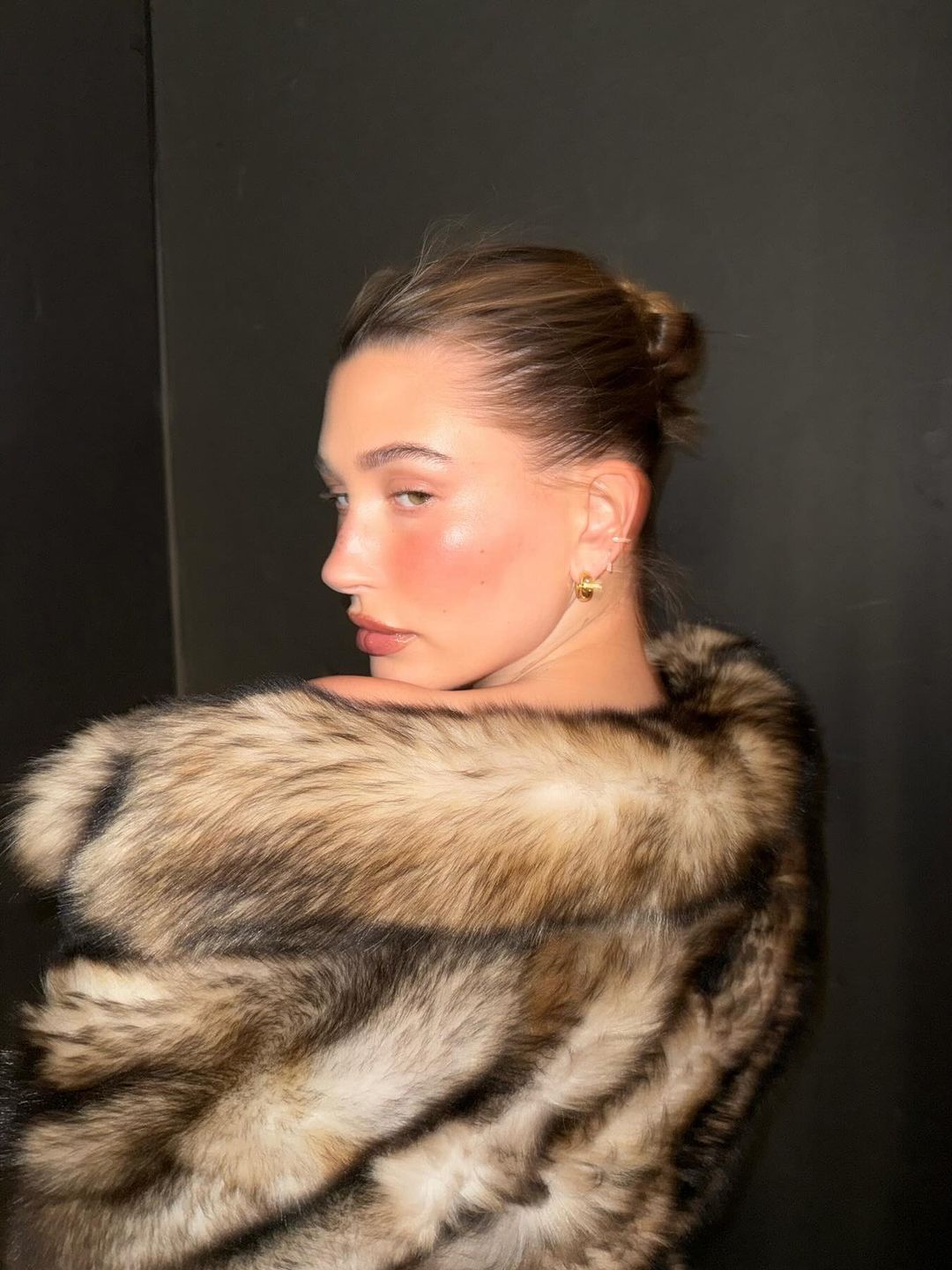 Hailey Bieber poses for a photo with no makeup in a fur coat