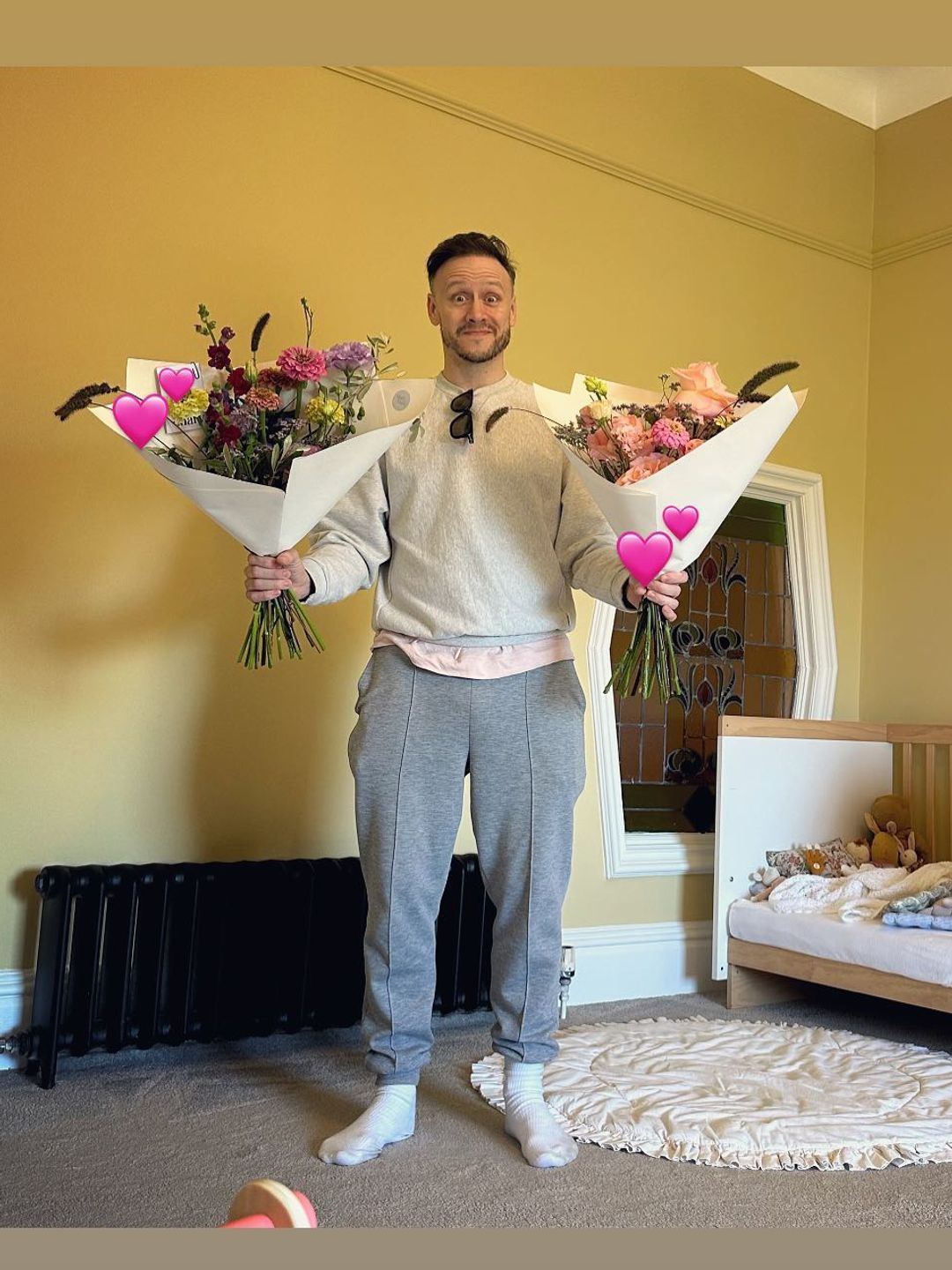 man posing in nursery with two bouquets