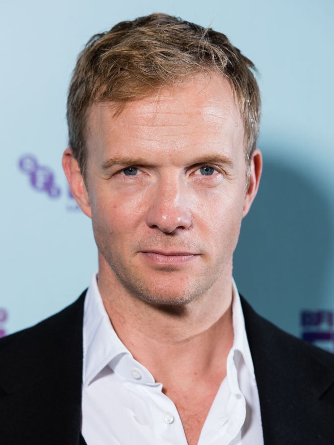 Close up of Rupert Penry-Jones. He is wearing a black suit and white shirt. 