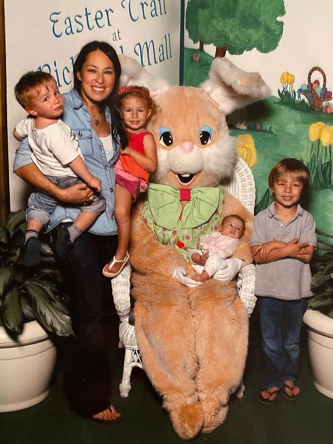 Joanna holding two children in her arms stood next to a person in an Easter Bunny costume who is sat next to Drake, and holding a baby Emmie