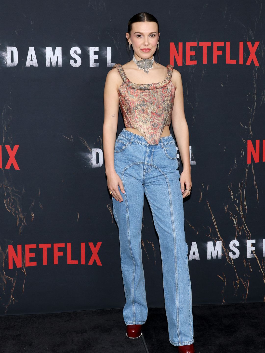Millie Bobby Brown attends the "Damsel" Photo Call in NYC wearing jeans and a corset