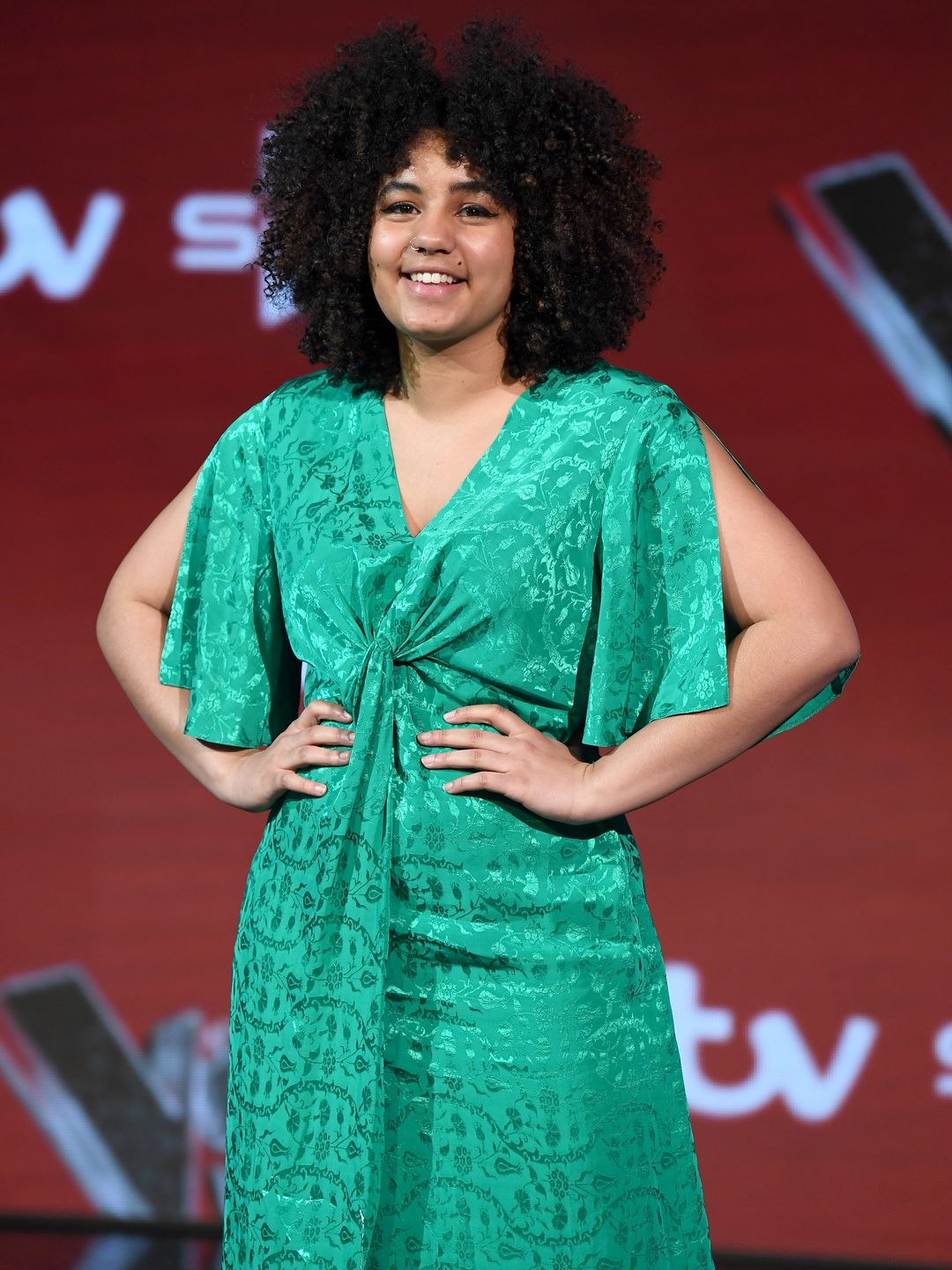 Ruti Olajugbagbe in a green dress with her arms on her hips